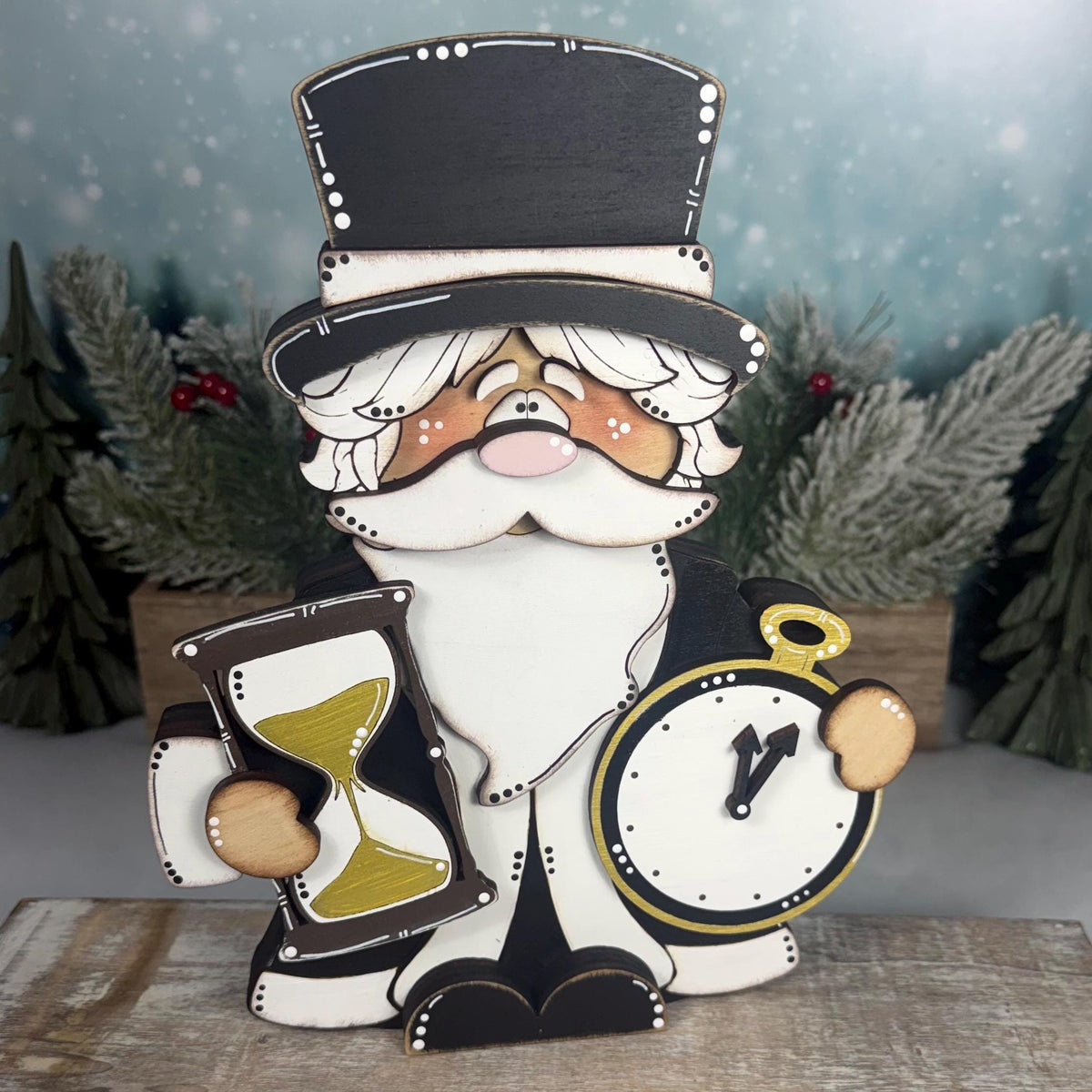 Hand-painted wooden Father Time shelf sitter featuring a black top hat, white beard, gold hourglass, and pocket watch. Layered rustic New Year's decoration displayed with snowy winter greenery.