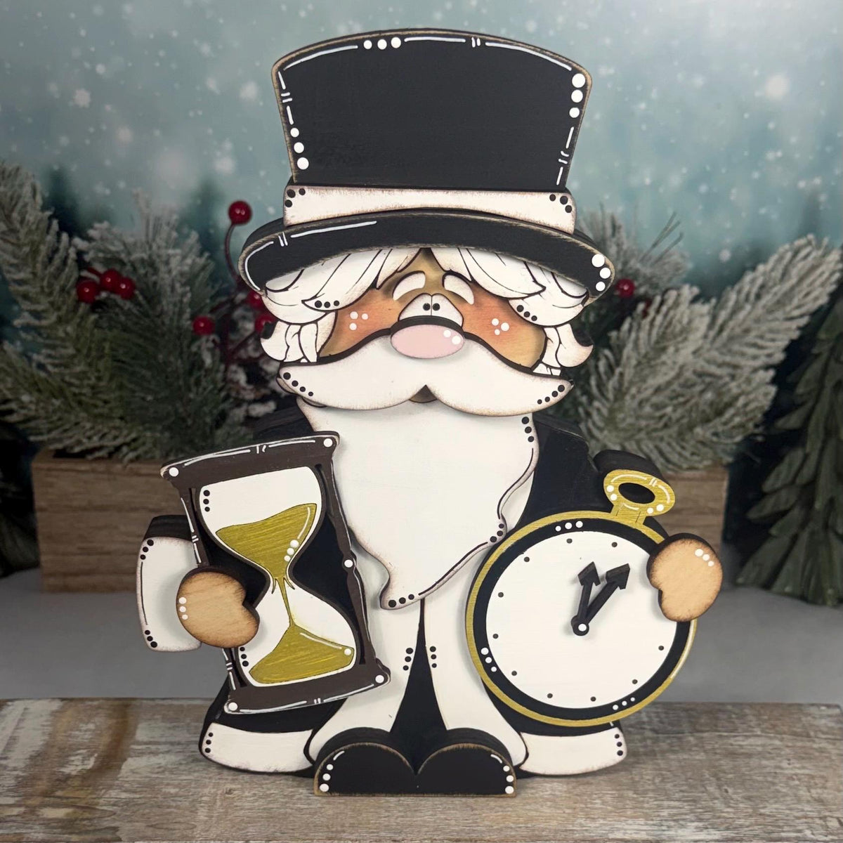 Hand-painted wooden Father Time shelf sitter featuring a black top hat, white beard, gold hourglass, and pocket watch. Layered rustic New Year's decoration displayed with snowy winter greenery.