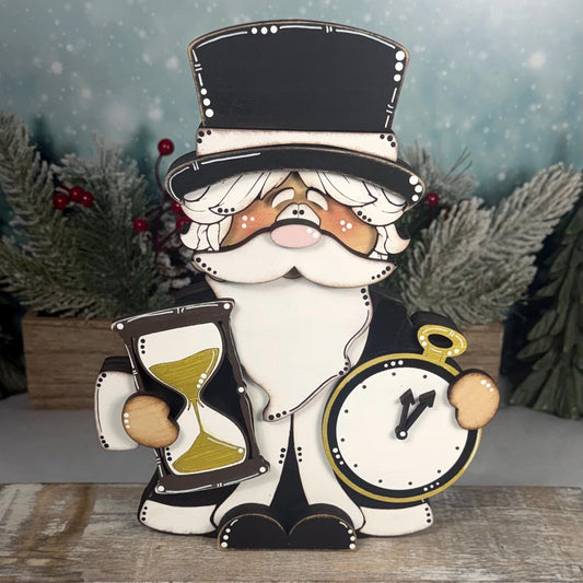 Hand-painted wooden Father Time shelf sitter featuring a black top hat, white beard, gold hourglass, and pocket watch. Layered rustic New Year's decoration displayed with snowy winter greenery.
